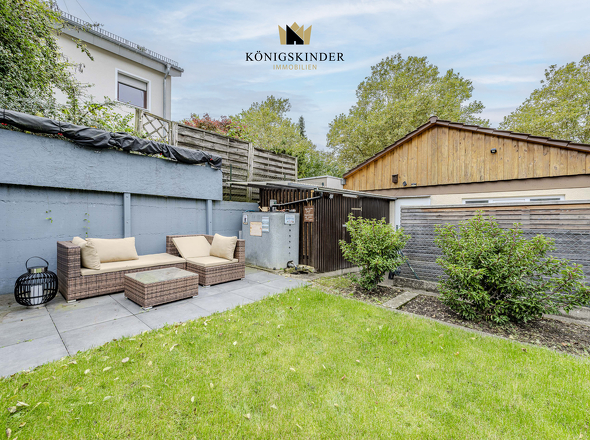 Grüner Garten mit funktionalem Geräteschuppen und seitlichem Garagenzugang.