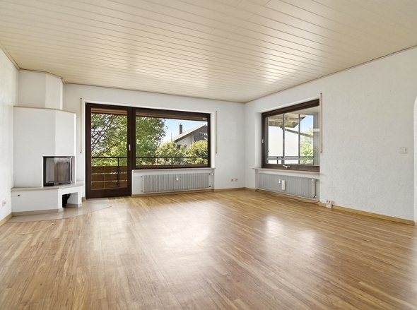 Helles Wohnzimmer mit Kamin und Zugang zum Balkon